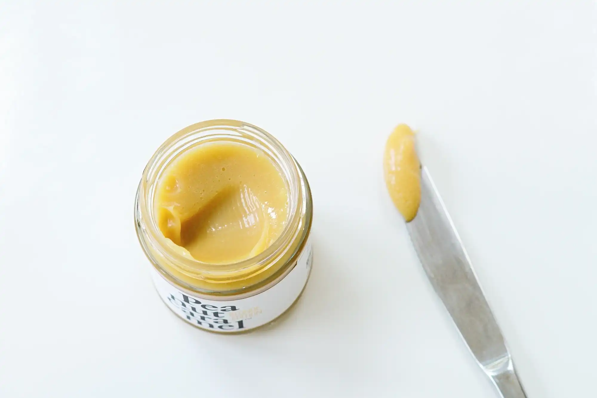 A photograph of an open jar of Peanut Caramel with a knife